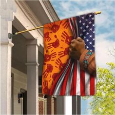 an american flag with hand prints on it hanging from the side of a house in front of a blue sky