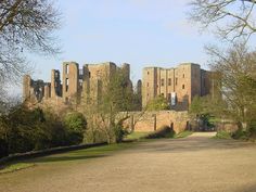 an old castle sits in the middle of a dirt road with trees on both sides