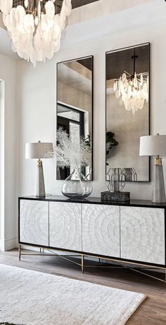 a white and black dresser with two mirrors on it's sideboard next to a door