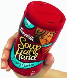 a hand holding a can of soup that is red