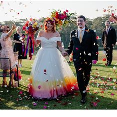 a bride and groom walk down the aisle as confetti flies around them