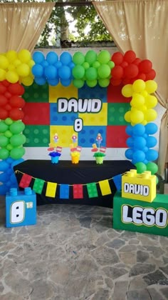 a birthday decoration with balloons and legos on the ground in front of a backdrop