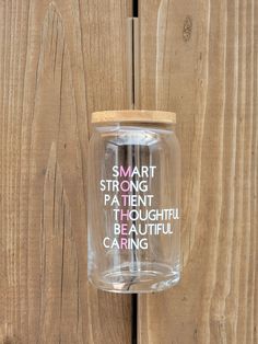 a clear glass jar with words on it hanging from a wooden fence, saying smart strong patient through beautiful beautiful caring