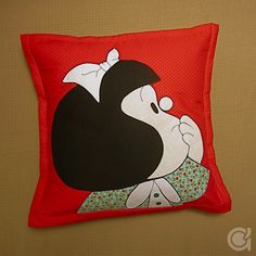 a red pillow with a black and white cartoon character on the front, sitting on a tan surface