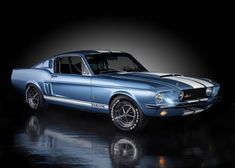 an old blue car with white stripes on the front and side, parked in a dark room