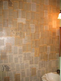 a bathroom with a sink, mirror and newspaper wallpaper on the walls in it