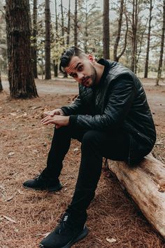 a man sitting on a log in the woods