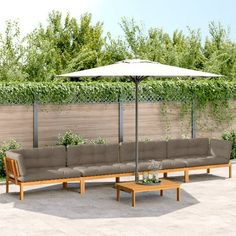 a couch and table with an umbrella in the middle of a patio area next to a fence