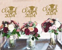 three vases filled with flowers sitting on top of a metal table next to each other