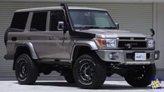 a silver and black four door suv parked in front of a garage wall with roller doors