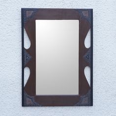 a mirror mounted to the side of a wall next to a white stucco wall with an intricate design