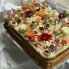 a cake with flowers on it sitting on top of a sheet of plastic wrapper