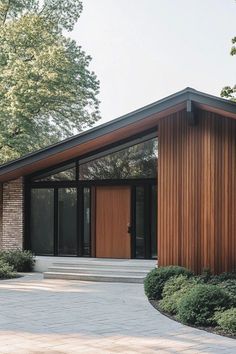 a modern house with wood siding and glass doors on the front door is surrounded by greenery