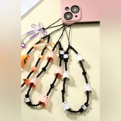 several necklaces are attached to a cell phone holder with beads and skulls on them