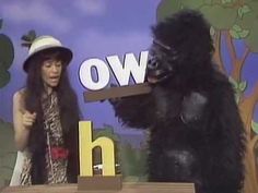 a woman standing next to a gorilla on top of a wooden block in front of a sign