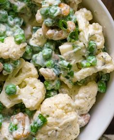 a white bowl filled with cauliflower and peas