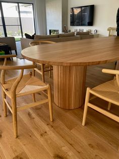 a large wooden table with chairs around it in a living room next to a couch