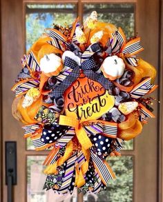 a wreath that says trick or treat is hanging on the front door with pumpkins