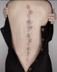 the back of a woman's neck with flowers and leaves on her lower back