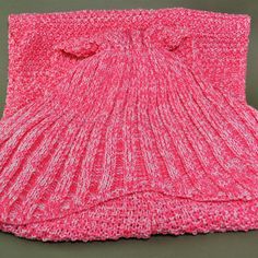 a pink knitted blanket sitting on top of a table