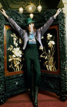 a man with his arms spread out in front of a large piece of art that has flowers on it