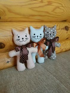 three stuffed cats sitting next to each other in front of a wooden wall and floor