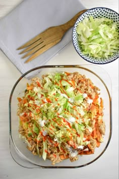 a bowl of coleslaw next to a plate of salad on a white table