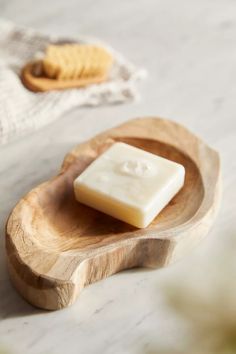 a bar of soap sitting on top of a wooden plate next to a spoon and napkin