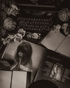 an old fashioned typewriter surrounded by books and papers with flowers on them, in black and white