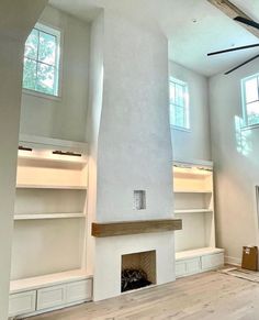 an empty living room with white walls and open shelves on either side of the fireplace