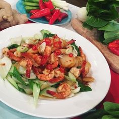 a white plate topped with shrimp and veggies on top of a red table cloth