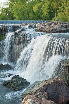 there is a large waterfall that has water coming out of the rocks and into the river