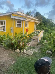 a small yellow house sitting on top of a lush green hillside