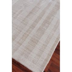 a white rug on top of a wooden floor next to a hardwood flooring plank