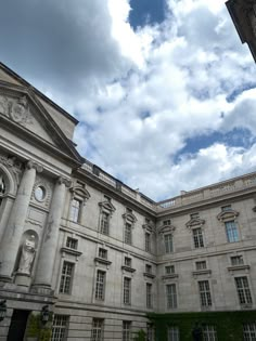 an old building with many windows on the front and side of it under a cloudy blue sky