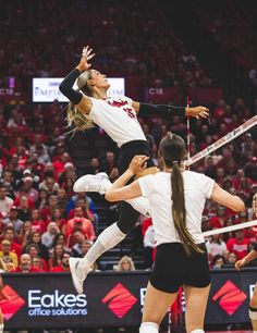 two women playing volleyball in front of an audience