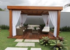 a wooden gazebo sitting on top of a lush green field next to a white couch