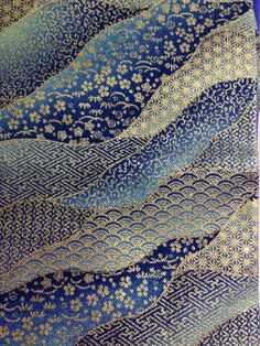 blue and gold patterned fabric with white flowers on the bottom, as well as an intricate design