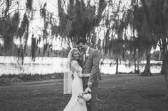 a bride and groom pose for a photo in front of the water at their wedding