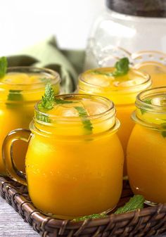 four mason jars filled with orange juice and mint garnish