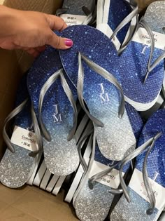 a box full of blue and silver flip flops with the letter m on them