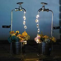 two metal buckets filled with flowers and lights