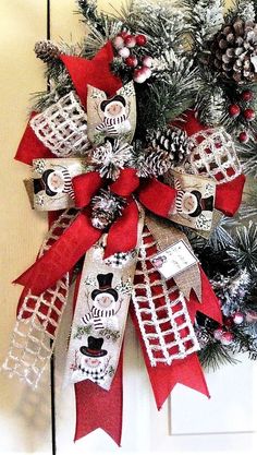 a red and white christmas wreath with snowmen, pine cones and lace on the front door