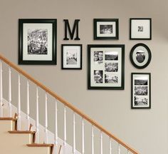 there are many pictures on the wall above the stairs in this house, and one is framed with black and white photos