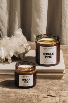 two candles sitting on top of a wooden table next to crystal rocks and a book