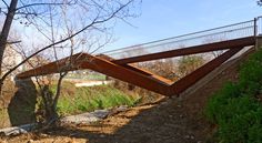 a wooden bridge over a small stream in the middle of a park with grass and trees