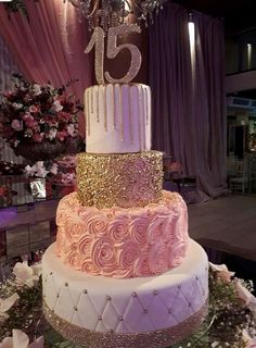 a three tiered cake with pink and white frosting on top is surrounded by flowers