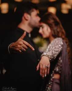 a man and woman standing next to each other with their fingers pointing at the camera