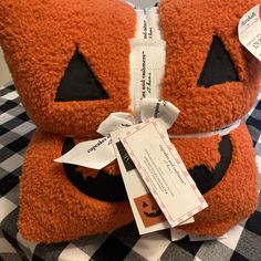 an orange teddy bear with a white ribbon around it's neck sitting on a checkered table cloth