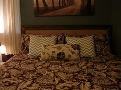 a bed with two pillows on it and a painting hanging above the headboard behind it